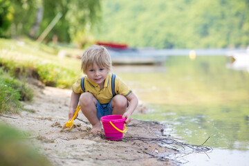 Wall Mural - Little toddler child, cute boy, playing with toys in the sand on a lake