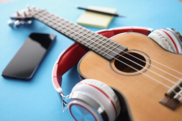 Wall Mural - Wooden guitar headphones. and smartphone on blue background