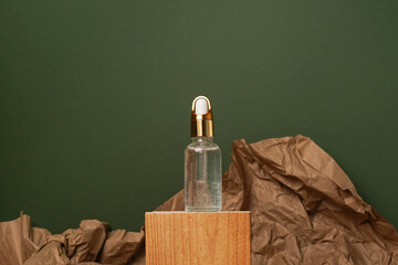 cosmetic glass bottle with skin care oil on wood podium on green background