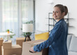 © StockPhotoPro - Happy woman carrying boxes in her new home