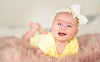 Cute baby portrait girl on bed in bright interior. Baby background.