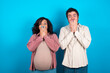 © Roquillo - Vivacious young couple expecting a baby standing against blue background, giggles joyfully, covers mouth, has natural laughter, hears positive story or funny anecdote