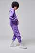 Hip-hop style of young black man wear purple set of tracksuit isolated on gray background