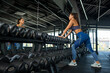 © nazarovsergey - Sporty young woman standing near mirror eaning on dumbbell rack in gym