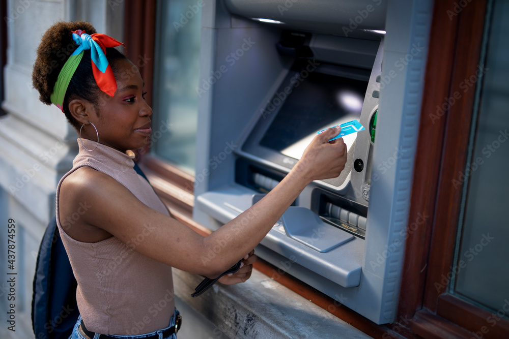 Beautiful african womn using ATM machine. Attractive young woman ...