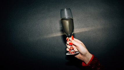 Poster - Birthday cheer. Holiday party. Happy celebration. Advertising background. Unrecognizable woman red manicure holding champagne glass isolated black light splash copy space.