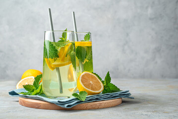 Refreshing lemonade with mint on a gray background. An invigorating summer drink. Side view, copy space.