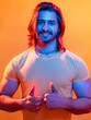© golubovy - Hipster male portrait. Neon light people. Positive lifestyle. Supportive gesture. Confident happy muscular man showing thumbs up like sign in blue red vibrant color glow isolated orange.