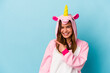 Young caucasian woman wearing a unicorn pajama isolated on blue background smiling and pointing aside, showing something at blank space.