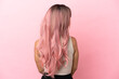 © luismolinero - Young mixed race woman with pink hair isolated on pink background in back position and looking side