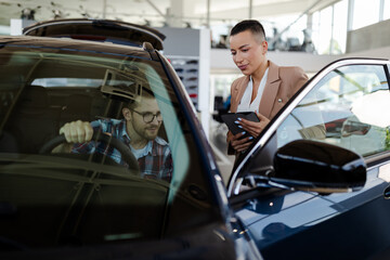 Wall Mural - Test drive. Car buyer sitting in auto, choosing new automobile with seller In store.