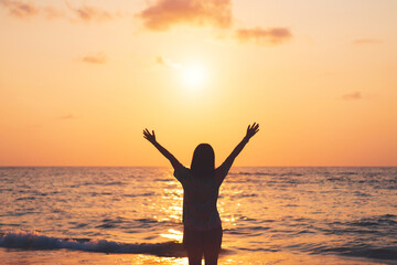 Poster - Copy space of woman rise hand up on sunset sky at beach and island background.