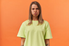 Cute Playful Young Woman In Yellow Tshirt Making Funny Face And Looking At Camera Isolated Over Orange Background