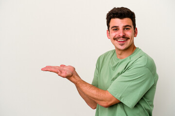 Young caucasian man isolated on white background holding a copy space on a palm.