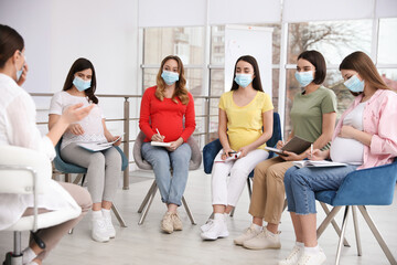 Canvas Print - Group of pregnant women and midwife in protective masks at courses for expectant mothers indoors