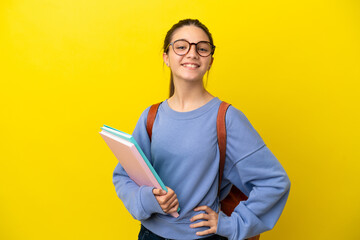 Wall Mural - Student kid woman over isolated yellow background posing with arms at hip and smiling