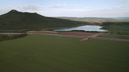 Wall Mural - drone flight over beautiful nature with green rolling fields and a newly built highway that passes t