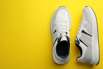 Pair of stylish sports shoes on yellow background, flat lay. Space for text