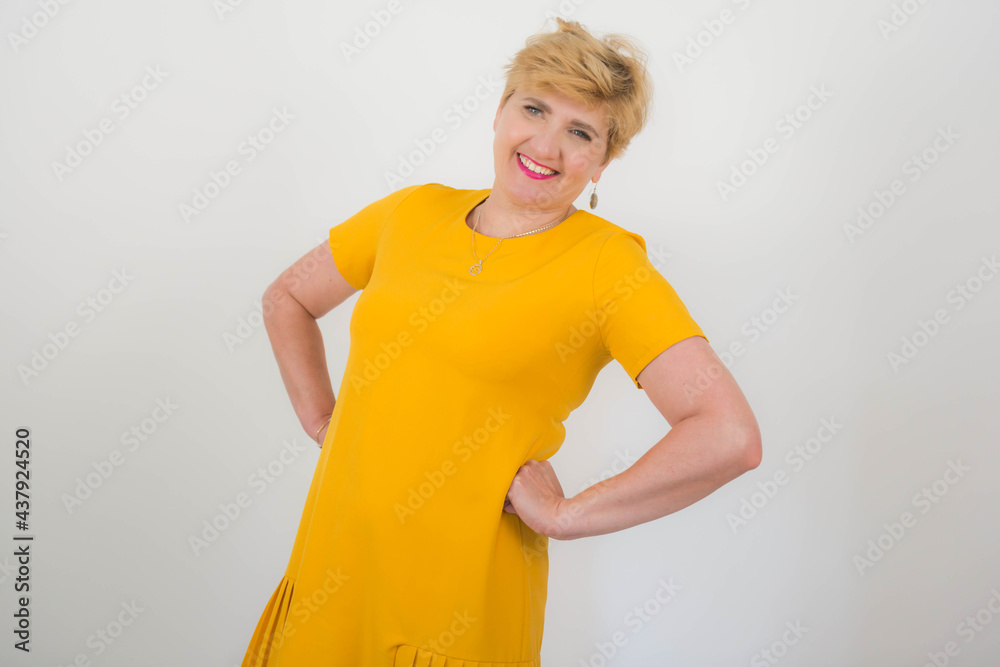 Ładna, elegancka kobieta w średnim wieku w żółtej sukience. - obrazy, fototapety, plakaty 