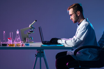 Poster - medical researcher next to laptop. medic works in a dark lab. concept - it conducts medical researc.