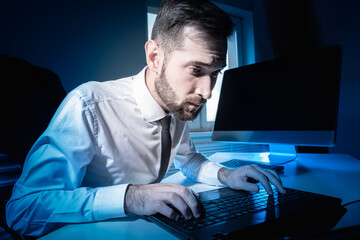 Poster - An office worker works overtime. Portrait of an office worker working at night. Close-up of man who is printing something. Concept - person is forced to work in overtime. Manager in a dark office.