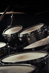 Detailed view over the tombs of a drumset in a dark room