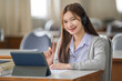 © EduLife Photos - Young interactive happy Asian teenage girl university student studying and presenting her lesson online via video call on a digital tablet in the classroom alone herself. Education stock photo