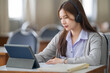 © EduLife Photos - Young interactive happy Asian teenage girl university student studying and presenting her lesson online via video call on a digital tablet in the classroom alone herself. Education stock photo