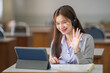 © EduLife Photos - Young interactive happy Asian teenage girl university student studying and presenting her lesson online via video call on a digital tablet in the classroom alone herself. Education stock photo
