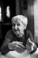 Wall Mural - Old woman talks by gesturing with her hands. Black and white portrait.