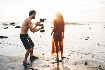 Slender female model and photographer working on sandy beach