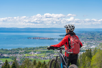 happy, active senior woman admiring a awesome view over Lake Constance with snow capped Swiss mountains in background
