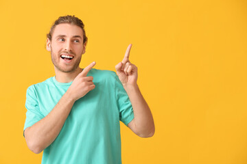 Poster - Handsome man pointing at something on color background