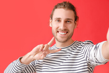 Poster - Young man showing victory gesture on color background