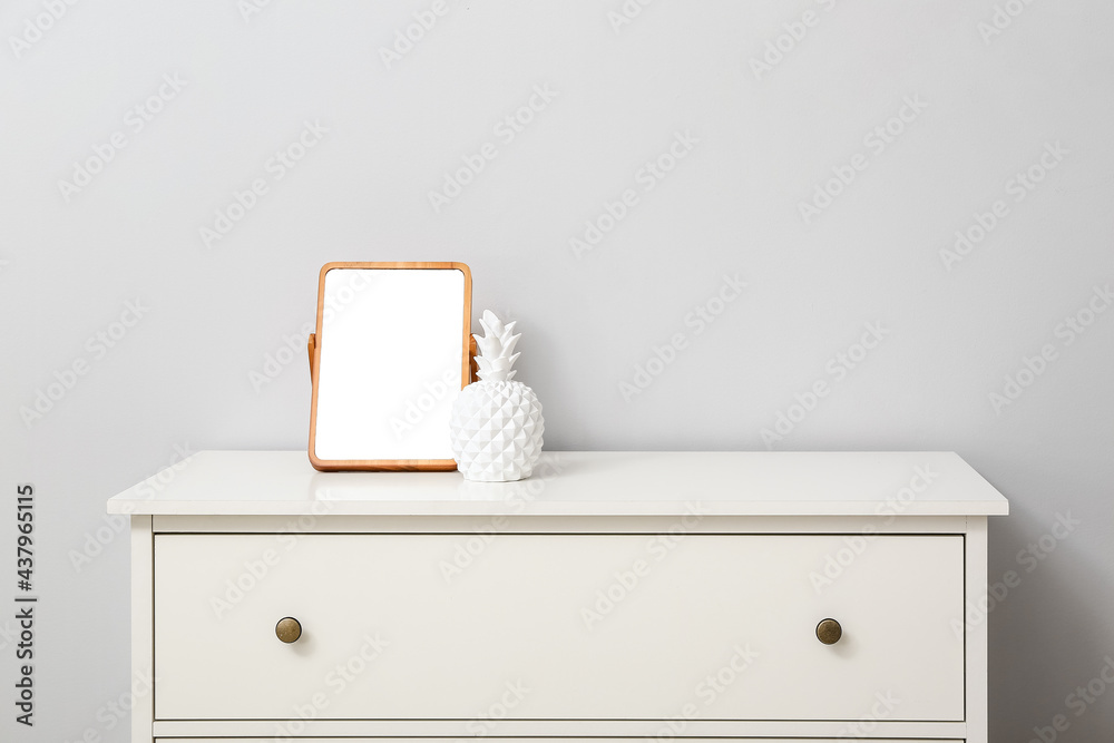 Mirror and decor on chest of drawers near light wall