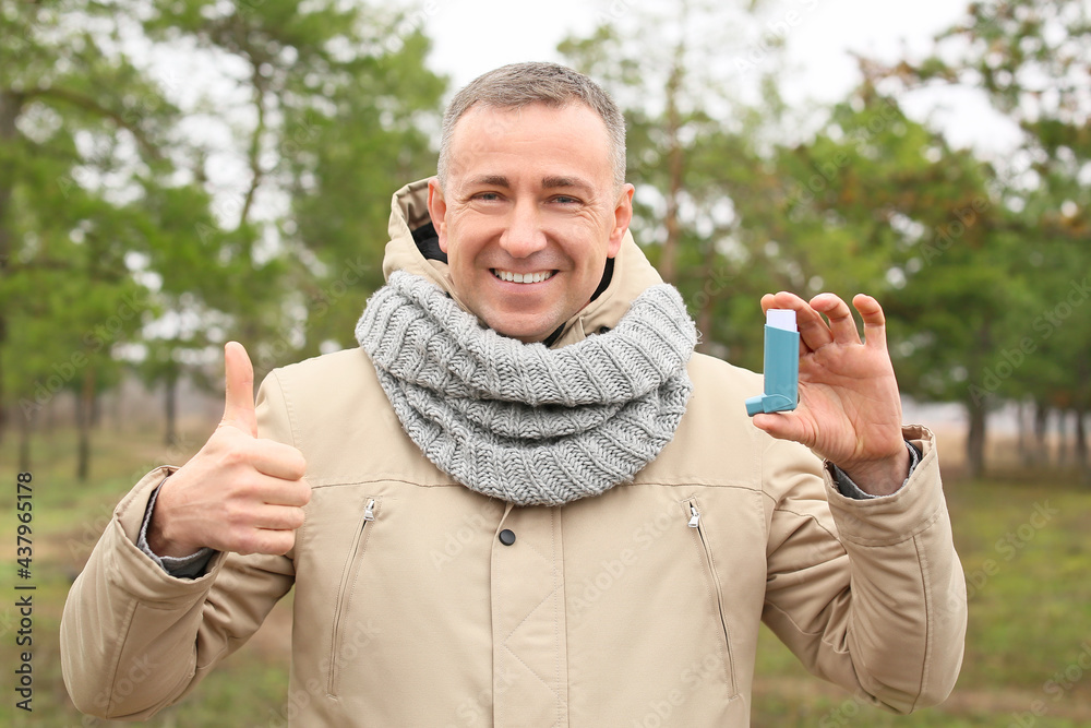 Senior man with inhaler showing thumb-up outdoors