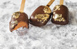 Popsicles, covered with chocolate, with a leaf of edible gold on top on an icy background with snow. Popsicle and sweet dessert on a stick.