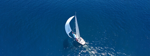 Wall Mural - Aerial drone ultra wide panoramic photo of beautiful sail boat with white sails cruising deep blue sea near Mediterranean destination port