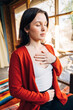 © Inti St. Clair - Close up of woman meditating at home with hand on heart and on stomach
