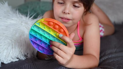 little girl plays with pop it sensory toy simple dimple. the baby clicks on colorful rainbow soft so