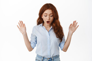 dropped something. shocked redhead girl looking down at surprising thing, checking out advertisement
