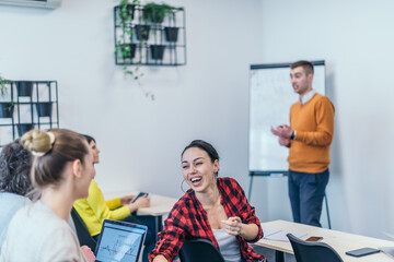 Wall Mural -  Multi-ethnic business group listening to a speaker while attending a business seminar at a modern workshop...