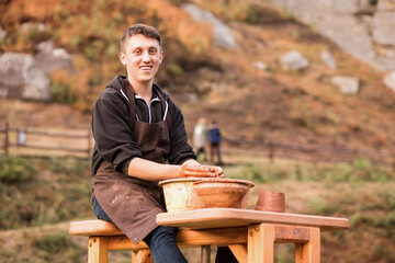 Man potter work with clay ware. Young handsome man potter on his workshop. 