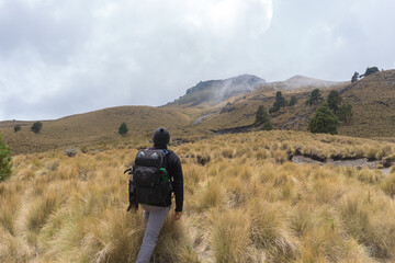 A male with a backpack hiking and climbing to the top of malinche volcanic mountain in Mexico