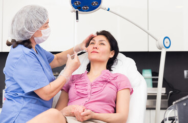 Wall Mural - Woman getting injection for facial correction procedure in esthetic clinic