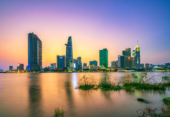 Wall Mural - Riverside city sunset moments in the sky at end of day brighter coal sparkling skyscrapers along beautiful river in Ho Chi Minh City, Vietnam