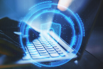 Poster - Close up of hands using laptop with abstract glowing shield lock on blurry background. Antivirus and protection concept. Double exposure.