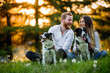 © NDABCREATIVITY - Happy couple playing with dog in the park outdoor