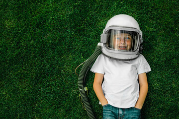 A child lies on the grass wearing an astronaut's helmet and dreams of great achievements!