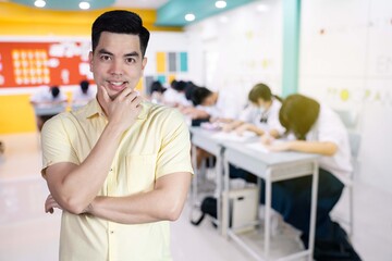 Wall Mural - Portrait handsome young asian man wearing a yellow shirt happy smile isolated on background blurred student study in class at school. Education concept.